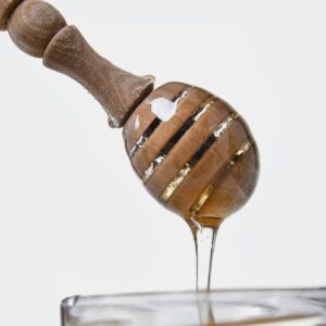 Sweet golden honey flowing from a wooden dipper, highlighting its thick, sticky texture.
