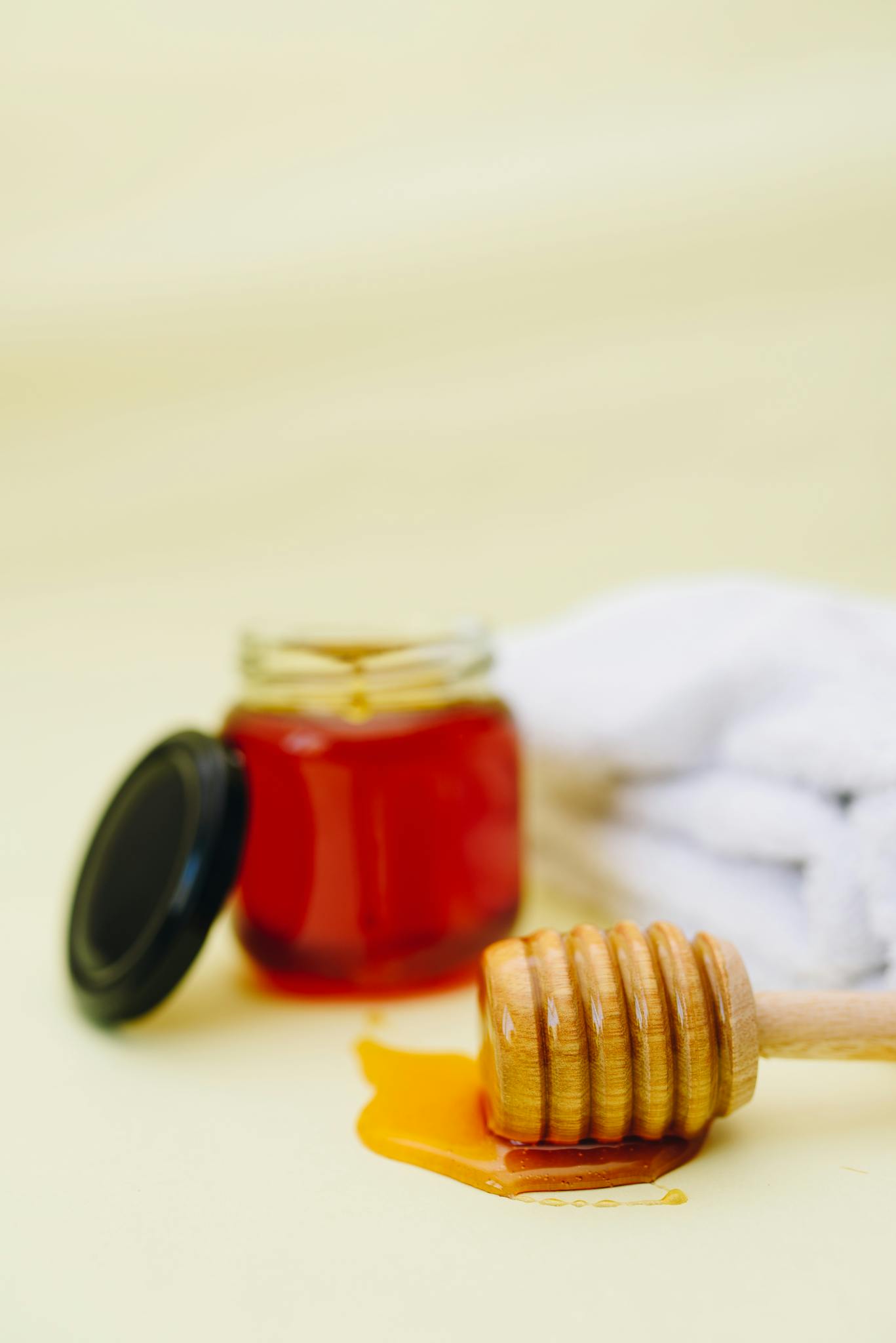 About 6 Warm-toned still life featuring golden honey in a jar with a wooden dipper on a soft background.